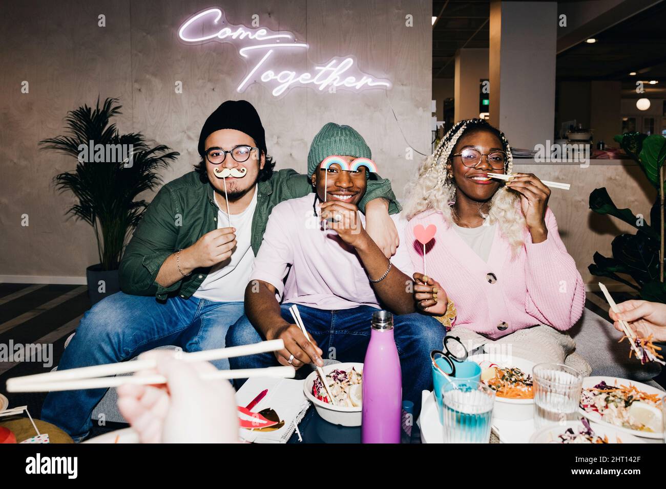 Portrait of happy multiracial male and female friends with props having