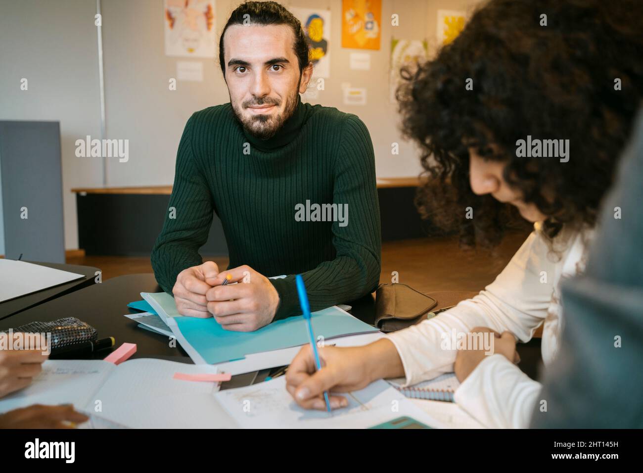 Portrait of confident young man sitting with female friend at table in university cafeteria Stock Photo