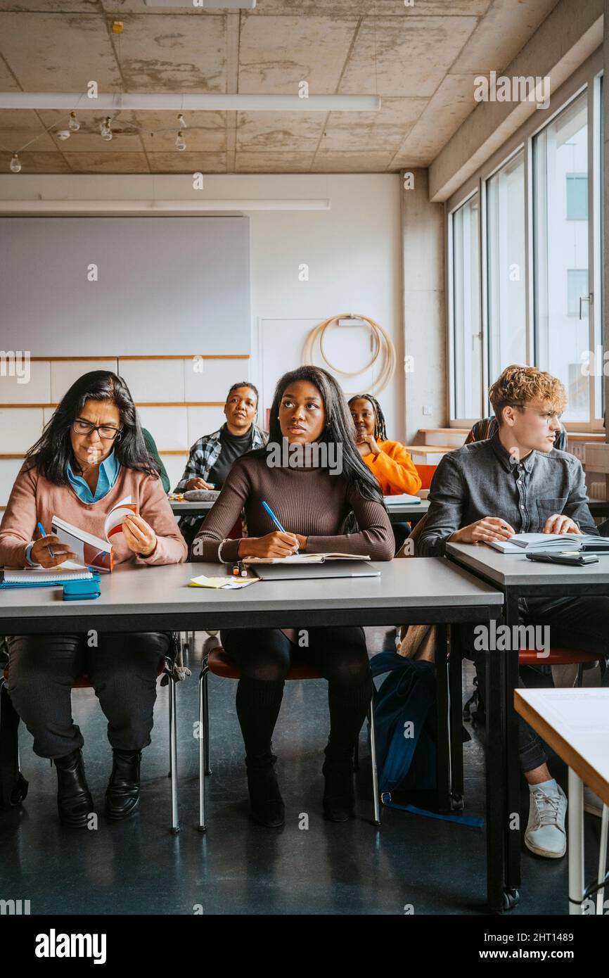 Multiracial university students sitting at desk learning in classroom Stock Photo