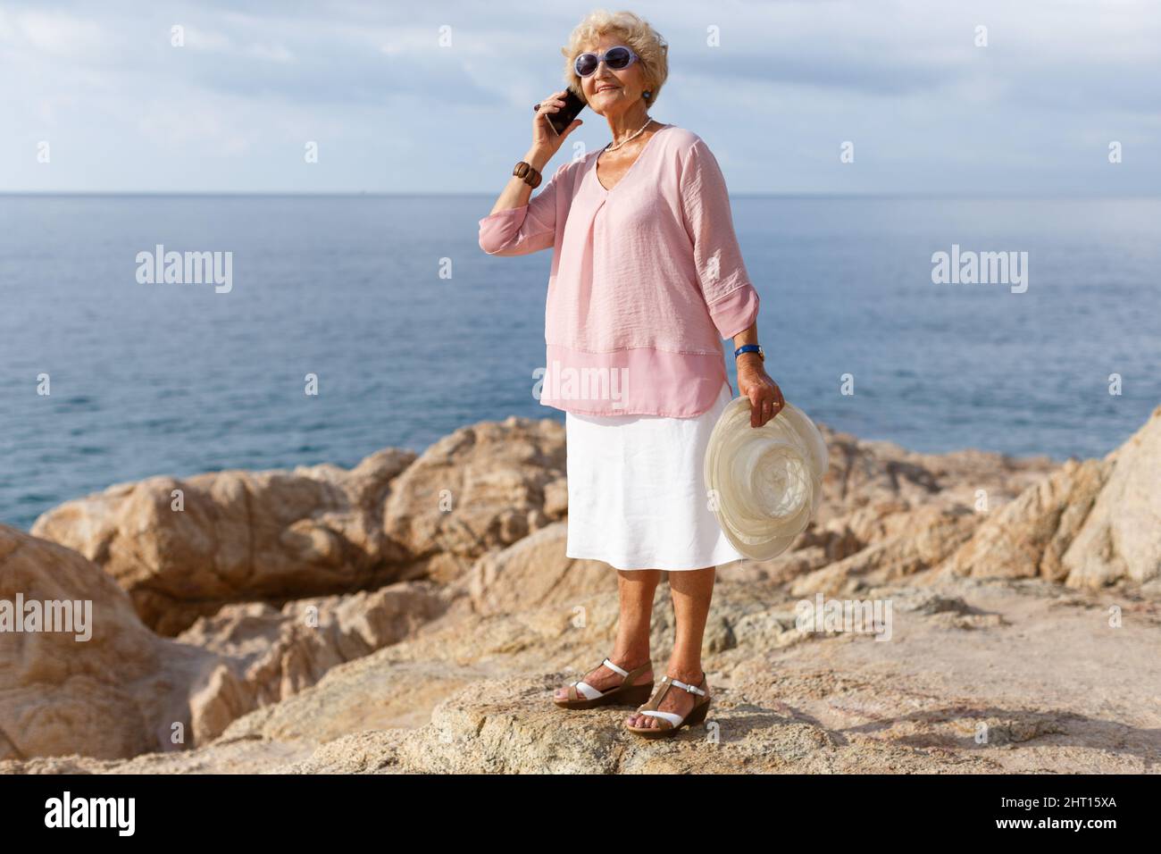 Aged woman talking on phone outdoors Stock Photo