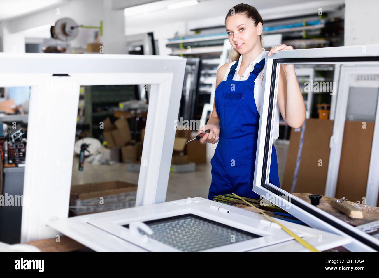 Workwoman assembling PVC window in workshop with manual tools Stock Photo