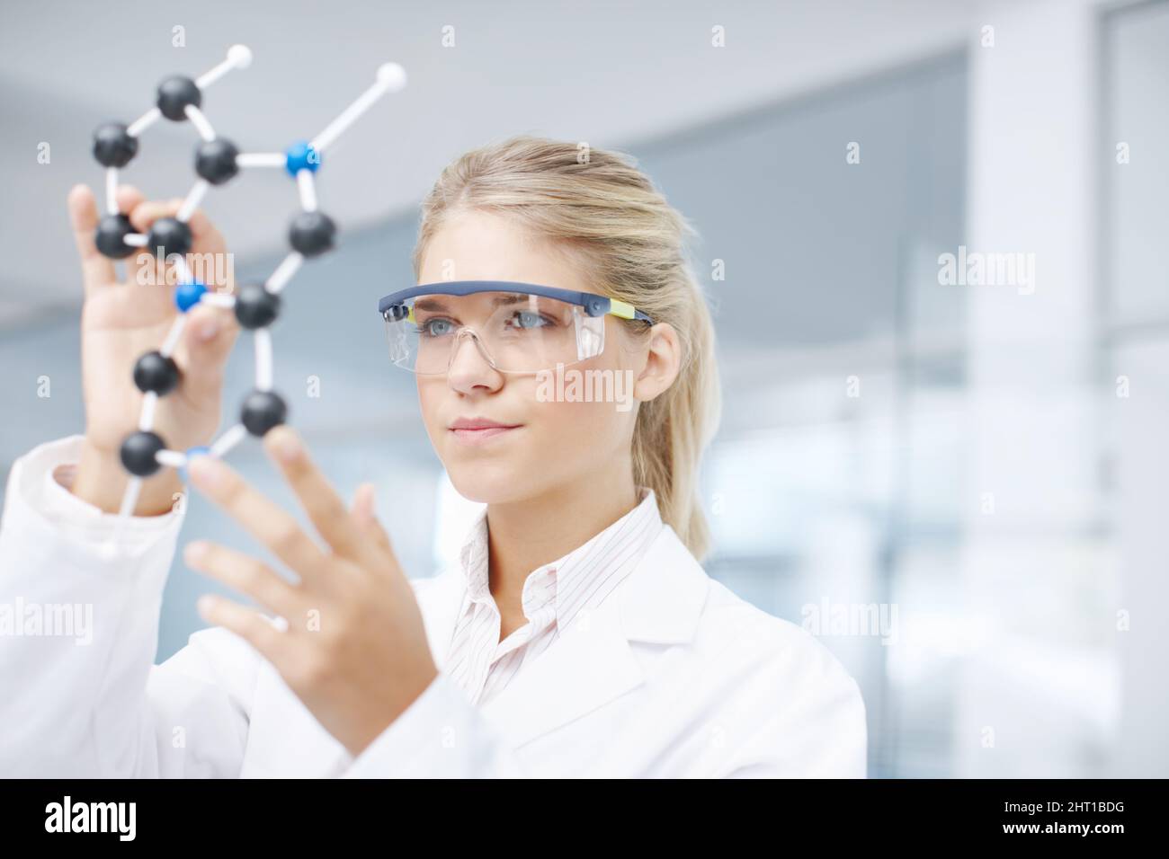 On the brink of a medical break-through. A gorgeous young scientist looking at a molecular structure model. Stock Photo
