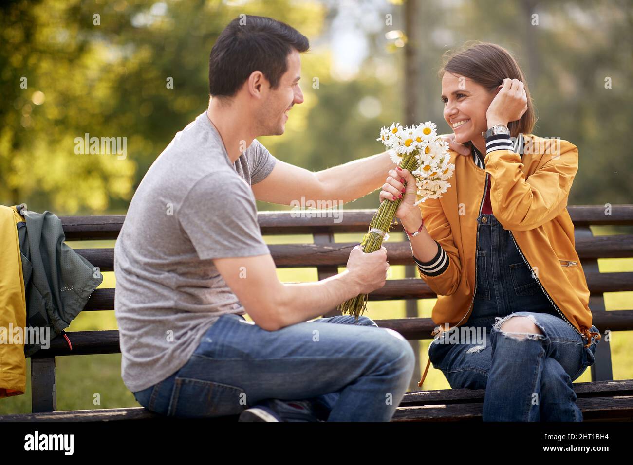 Man giving bouquet of flowers to a woman in a park; Happy couple ...