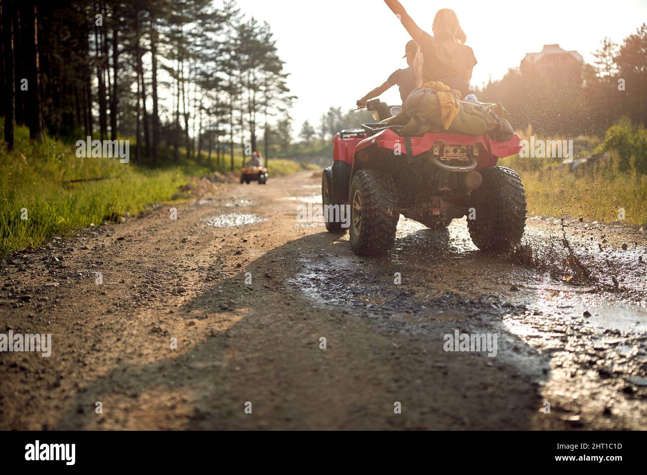 Young people on an off road adventure. Man driving quad with girlfriend sitting behind him, and enjoying the ride in mountains forest. Sport, freedom, Stock Photo
