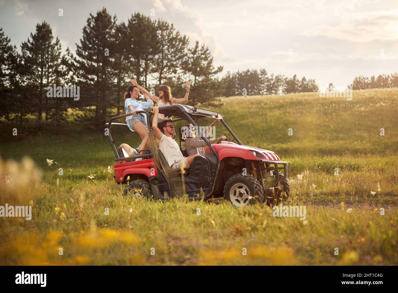 Friends cheering and enjoying beautiful sunny day while driving an off road buggy car on mountain nature. Freedom, friendship, happiness, nature conce Stock Photo