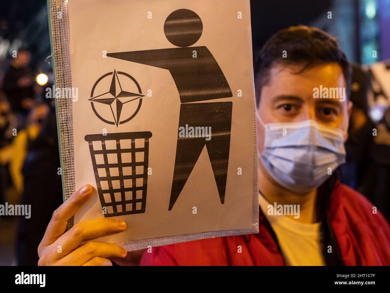 Madrid, Spain. 26th Feb, 2022. A protestor holds a placard with the NATO logo being through into a trash bin as he take part in a demonstration against Russia-Ukraine's war and NATO's role at the Puerta Del Sol square in Madrid, Spain on February 25, 2022. Credit: SOPA Images Limited/Alamy Live News Stock Photo