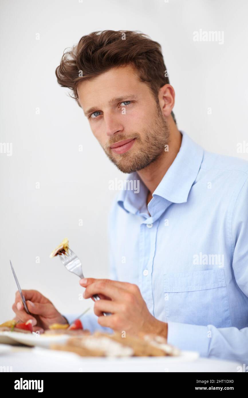I enjoy well-prepared food. Handsome young man enjoying a meal in a fine restaurant. Stock Photo