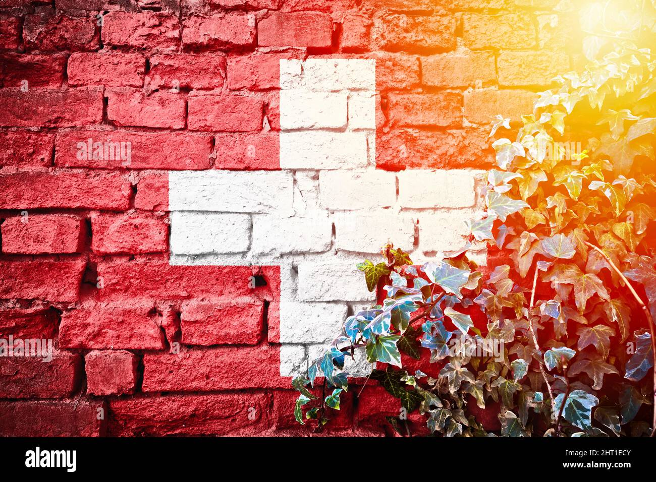Switzerland grunge flag on brick wall with ivy plant sun haze view, country symbol concept Stock Photo