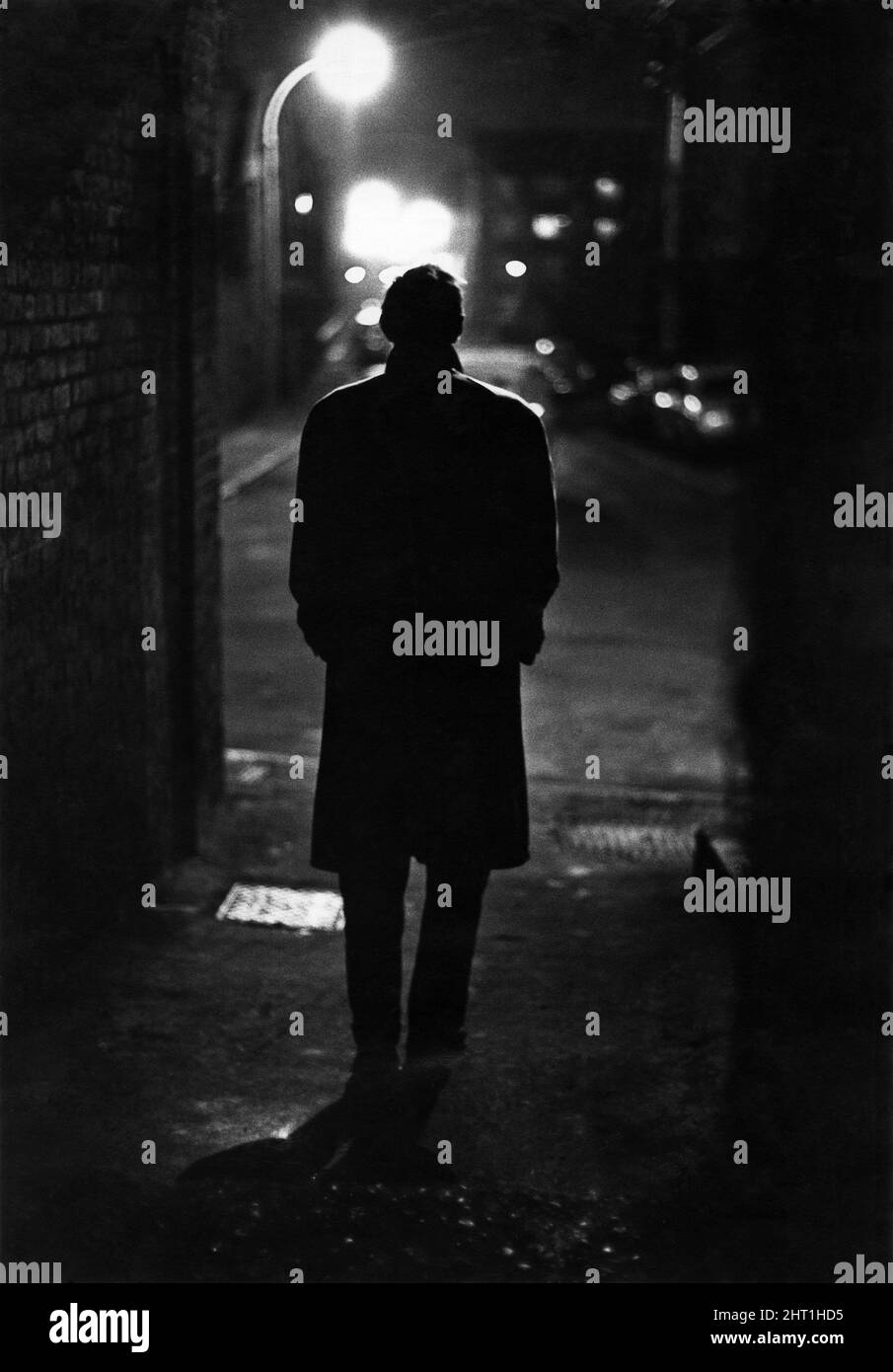 Avoiding the brightly lit thoroughfares of London, a National Service deserter dodges with the shadows in the back streets of the East End. February 1965 P035482 Stock Photo