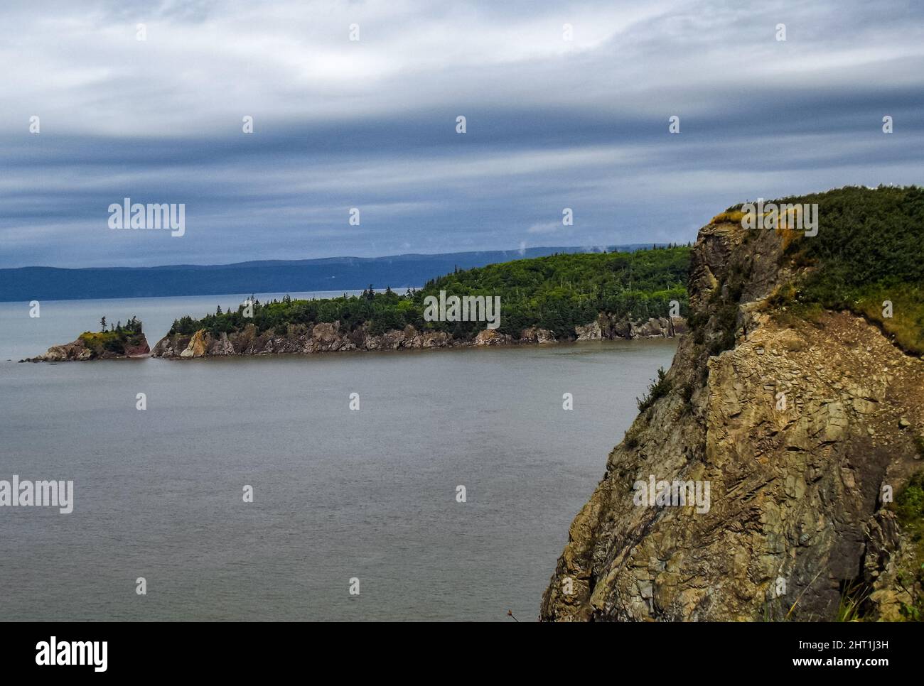 Landscape of the sea surrounded by cliffs and greenery under a stormy ...