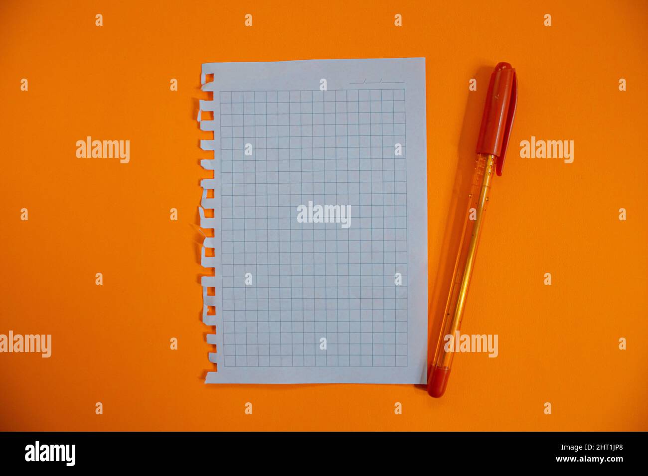 Blank notebook paper and pen isolated on orange background. Top view, flat lay. Stock Photo