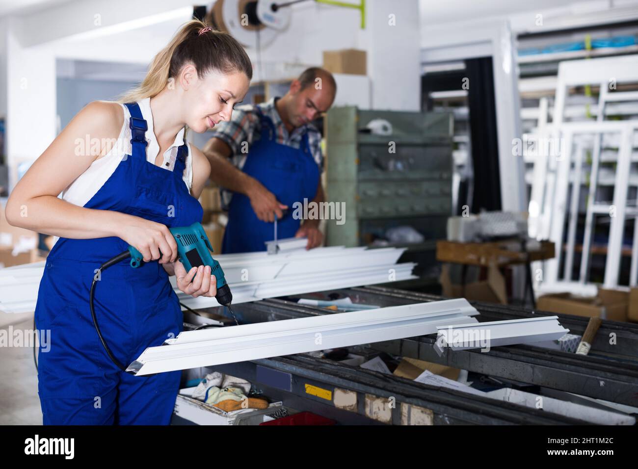 Workwoman using electric drill on plastic window fram Stock Photo