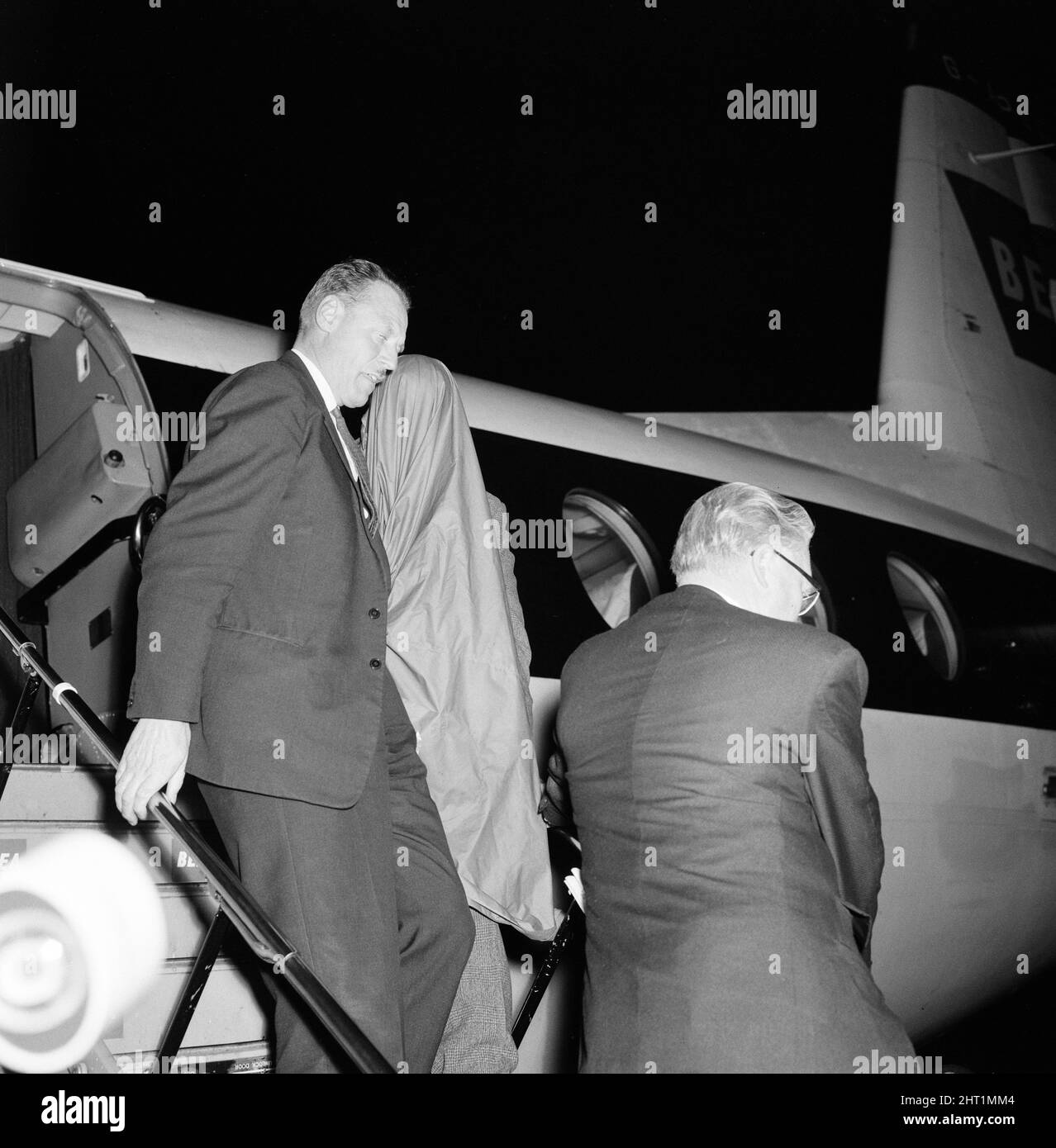 John Duddy, 37, one of the men that police wish to interview in connection with the shooting of three policemen in London, is guided down the steps of the plane on arrival at London Airport, from Glasgow, where he was detained this afternoon. 18th August 1966. Stock Photo