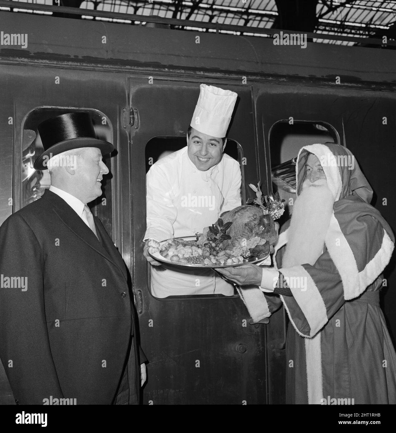 TURKEY TIME AT TURKEY STREET. When the 11.44am train left Liverpool Street Station today on board was a chef in full regalia accompanied by Santa Claus.  The chef , Mr Pedro Carol, was carrying a turkey weighing 20lbs that ws garnished on a silver platter.  To see the party off the Station Master wore his top hat.  The destination of the party and the turkey was Turkey Street Station about 20 minutes ride from Liverpool Street Station.  At Turkey Street a group of local children met the turkey and Father Christmas and the whole party marched through Turkey Street Village to a pub called The Tu Stock Photo
