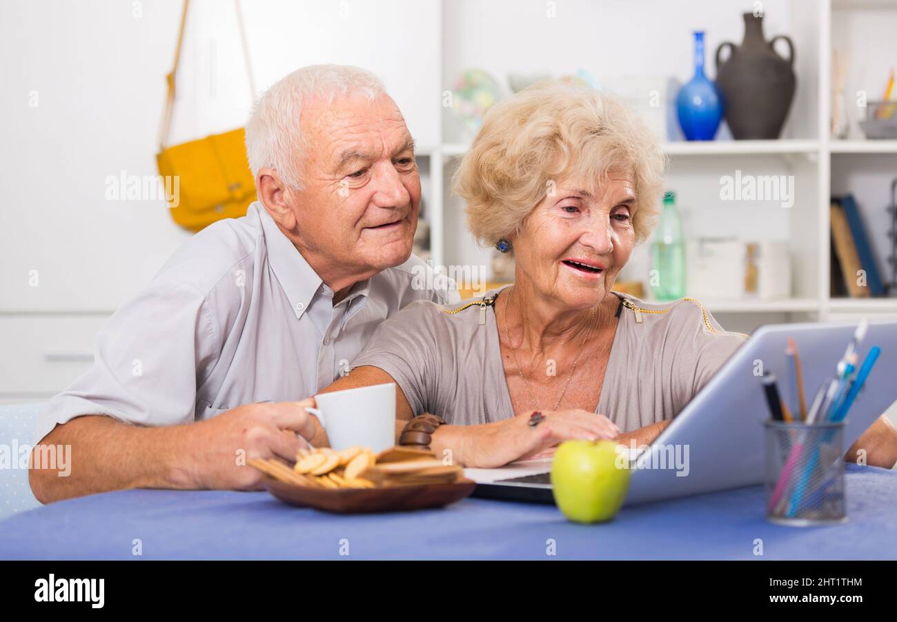 Cheerful mature spouses using laptop at home Stock Photo
