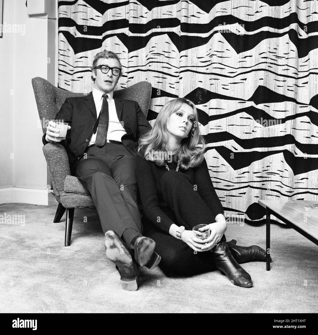 Actor Michael Caine pictured with French actress Miss Elizabeth Ercy in the flat of the Mirror's Donald Zec.  2nd December 1965. Stock Photo