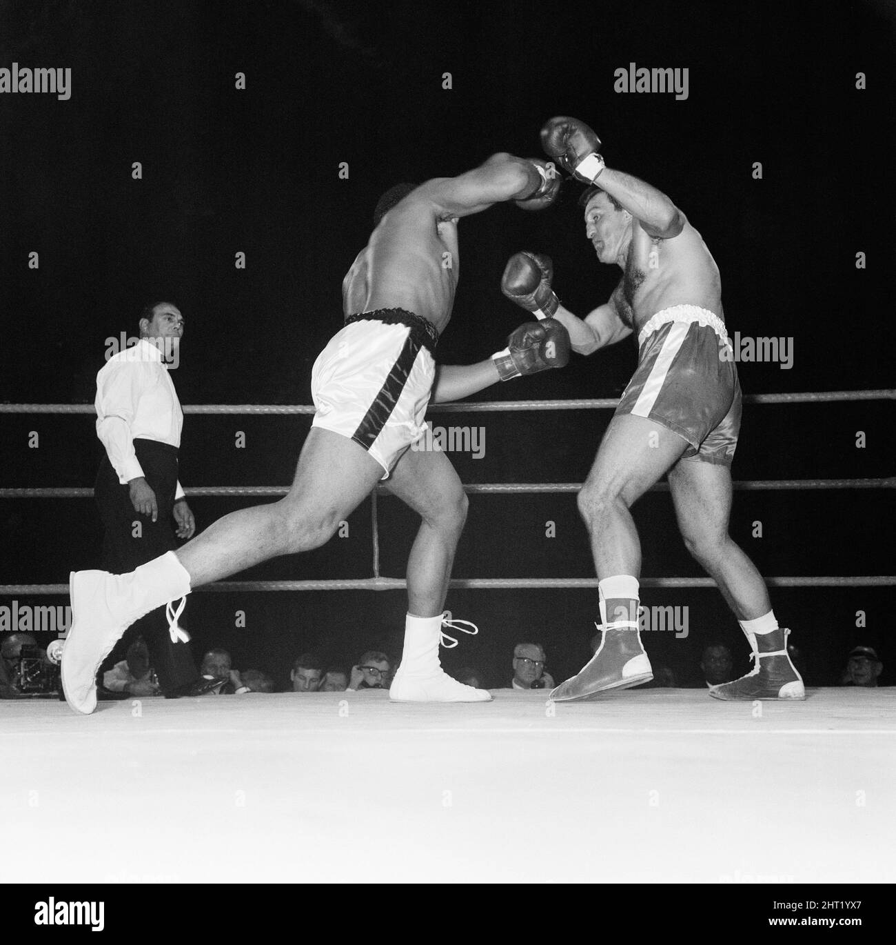 On August 6, 1966 at Earls Court Arena, Kensington, London, England, heavyweight champion Muhammad Ali, from Louisville, Kentucky, defended his title against Brian London, from Blackpool, England. Ali was undefeated at 24-0 coming in. London was 35-13. The fight was scheduled for 15 rounds. When asked if he wanted a rematch with Ali, London said, “Only if he ties a 56-pound weight to each leg…” Ali knocked-out London in the third round. (picture) Muhammad Ali unleashes an all-out assault on Brian London. Stock Photo