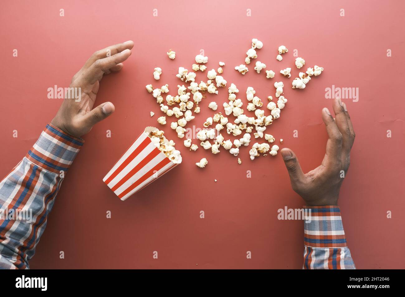 hand reaching for popcorn on red background  Stock Photo
