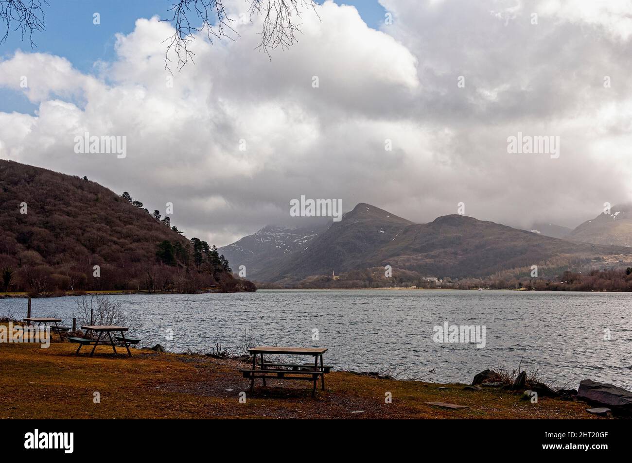 The snow dotted and cloud capped peaks of the rugged, mountains of the Snowdonia National Park as seen from the lakeside picnic area at Cei Llydan Stock Photo