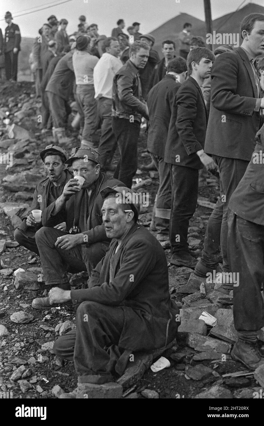 Aberfan - 21st October 1966 Miners take a short well earned break for a sit down,a  hot drink, cigarette and to gather their thoughts as the rescue effort carries on behind them.  The Aberfan disaster was a catastrophic collapse of a colliery spoil tip in the Welsh village of Aberfan, near Merthyr Tydfil. It was caused by a build-up of water in the accumulated rock and shale, which suddenly started to slide downhill in the form of slurry and engulfed The Pantglas Junior School below, on 21st October 1966, killing 116 children and 28 adults.   The original school site is now a memorial garden. Stock Photo
