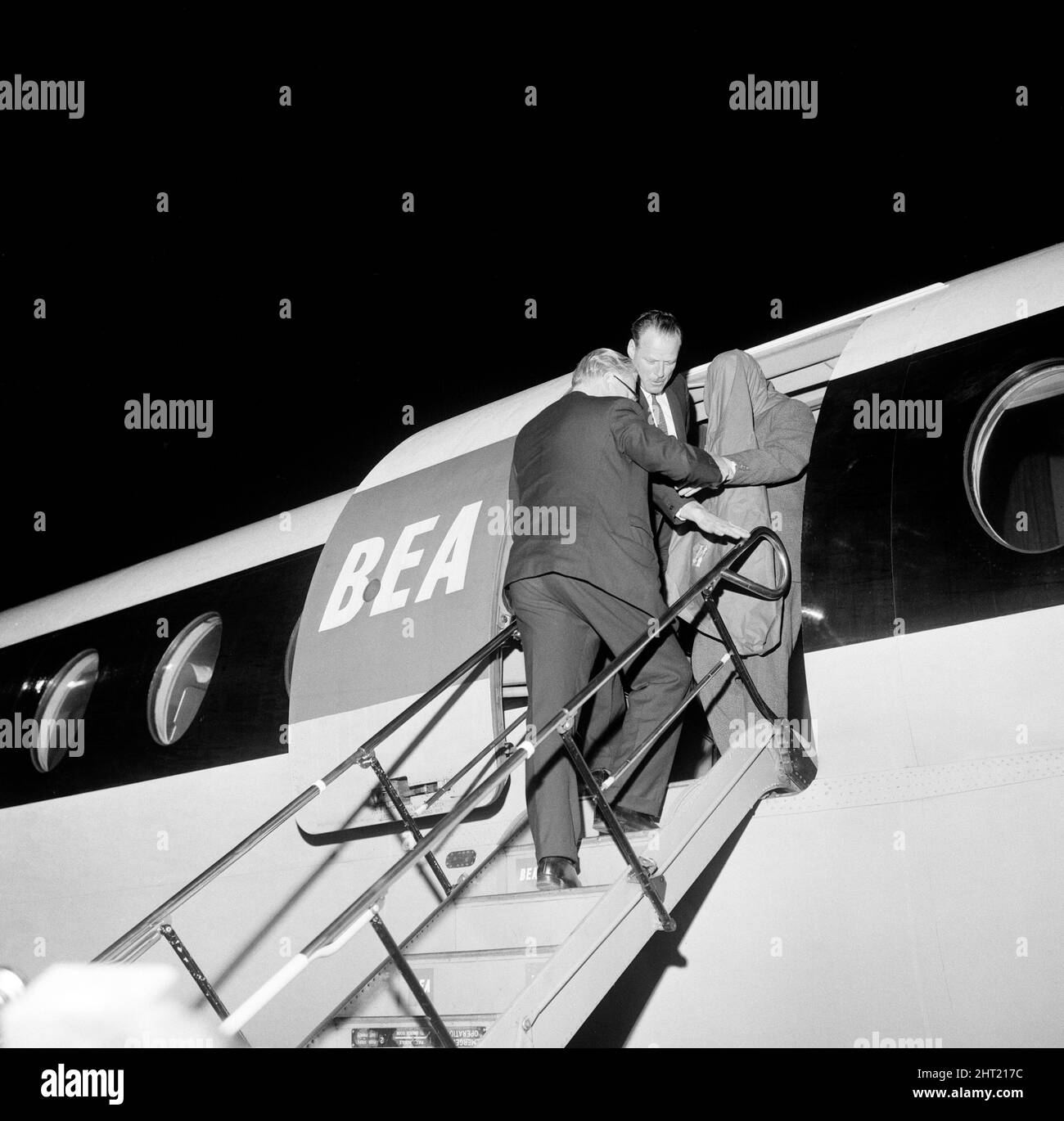 John Duddy, 37, one of the men that police wish to interview in connection with the shooting of three policemen in London, is guided down the steps of the plane on arrival at London Airport, from Glasgow, where he was detained this afternoon. 18th August 1966. Stock Photo