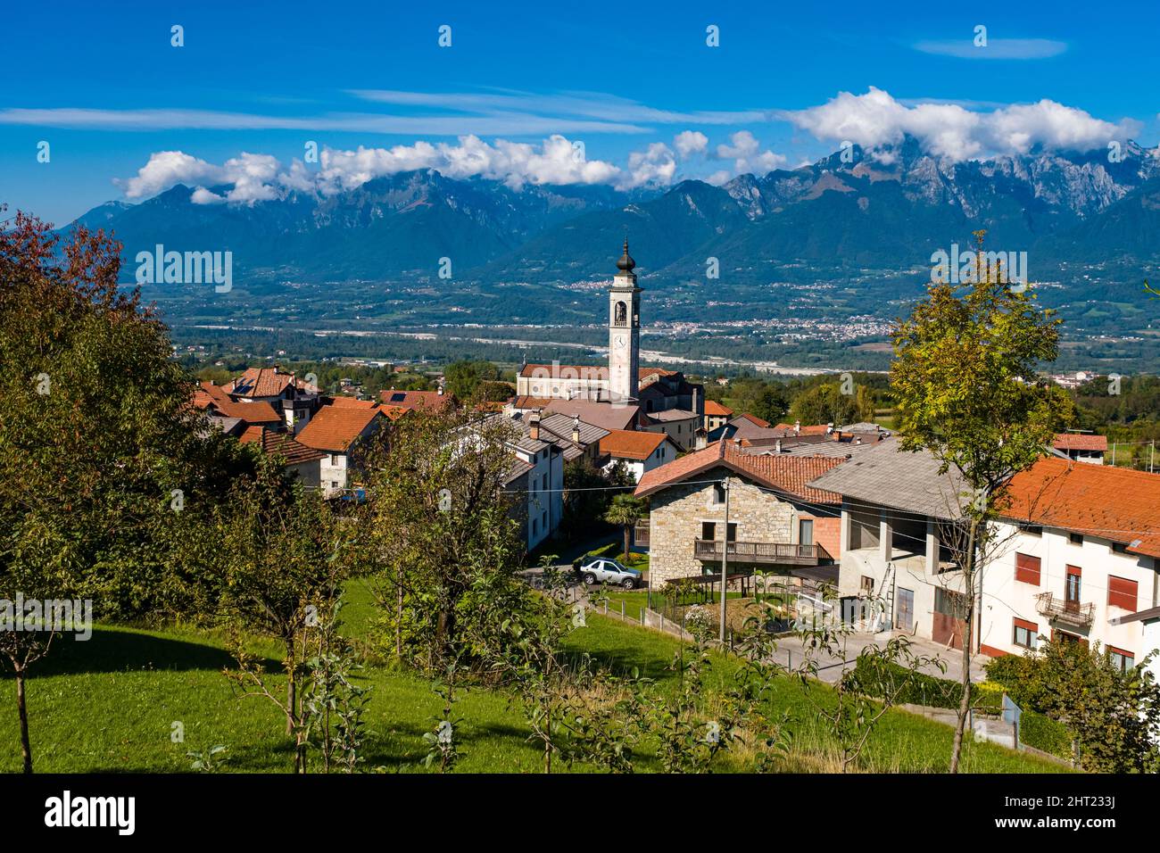 The village Carve with the church Chiesa di San Donnino Martire, the southern foothills of the Dolomites in the distance. Stock Photo