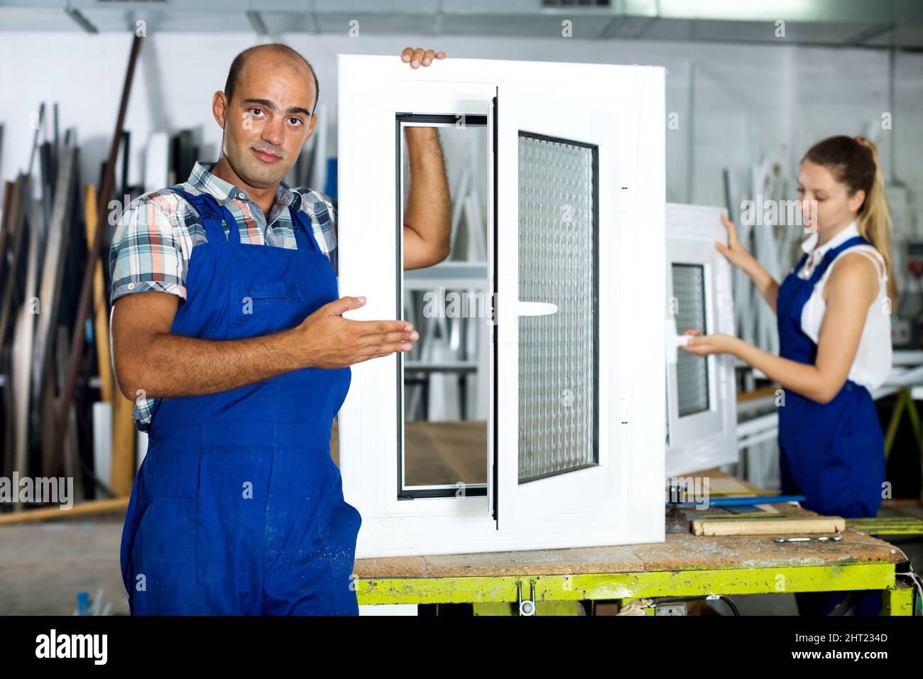 Workman in blue overalls demonstrating pvc window Stock Photo - Alamy