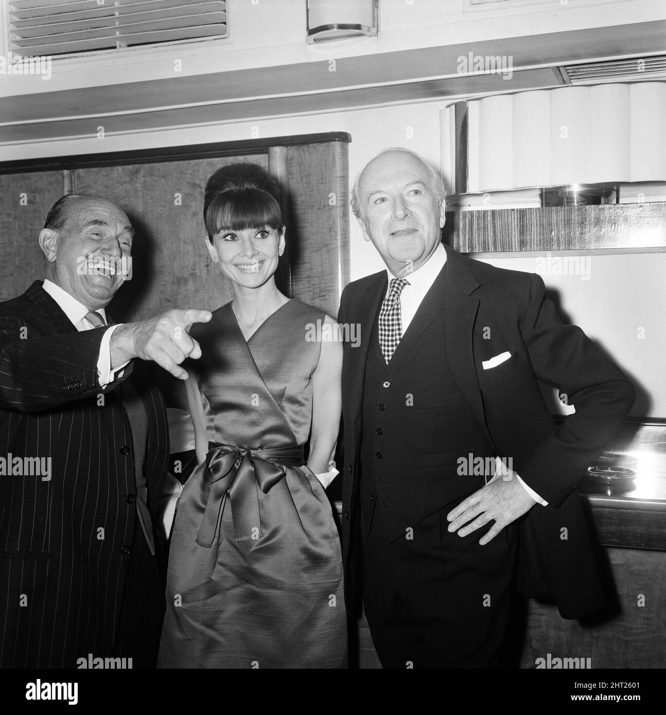 Actress Audrey Hepburn pictured with Jack L Warner (left) and Cecil Beaton at a press reception at the Savoy Hotel in London, held for some of the stars of the film 'My Fair Lady'. 19th January 1965. Stock Photo