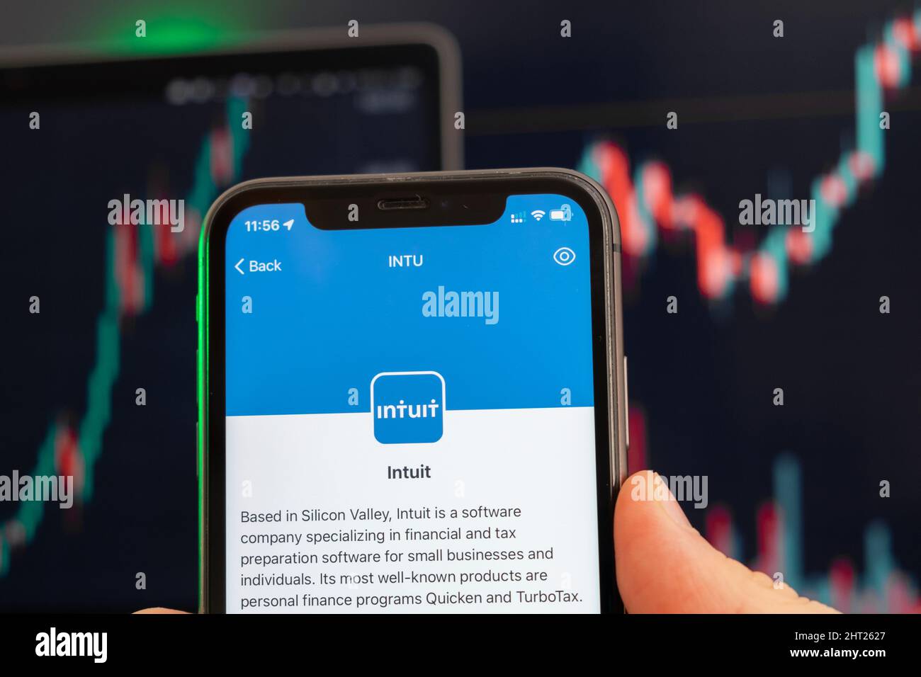 Intuit stock price increasing on the trading market with uptrend line graph bar chart on the background. Man holding a mobile phone with company logo, February 2022, San Francisco, USA Stock Photo