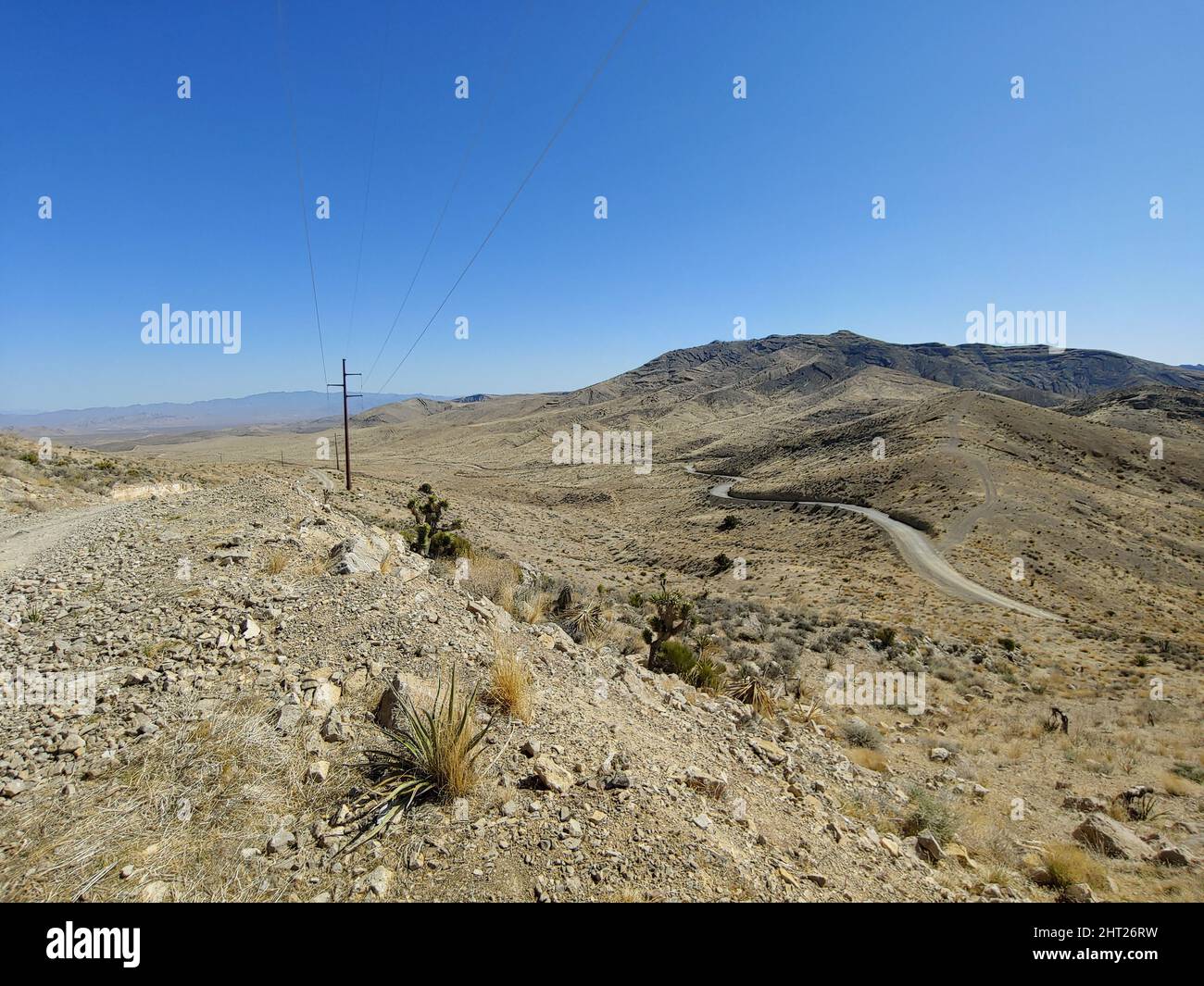 A view of a desert with hills and road wires across the roads Stock
