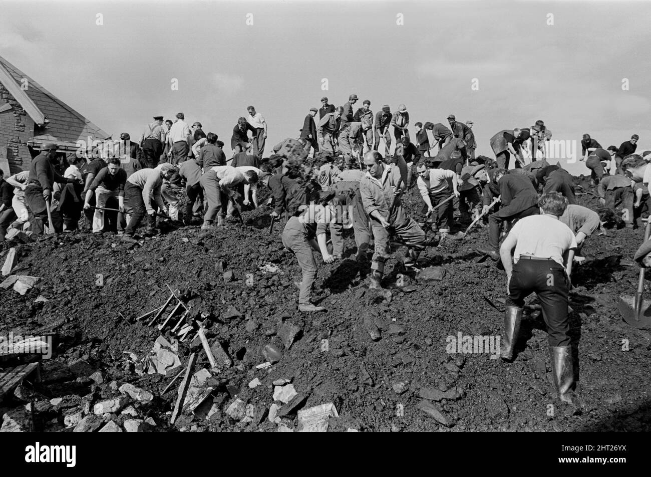 Aberfan, South Wales, circa 21st October 1966 Picture shows the mud and devastation caused when mining spoil from the hillside high above the town behind came down  and engulfed The Pantglas Junior School on 21st October 1966.   Rescuers trying to find victims and help, monist the mud and rubble around the school site.  The Aberfan disaster was a catastrophic collapse of a colliery spoil tip in the Welsh village of Aberfan, near Merthyr Tydfil. It was caused by a build-up of water in the accumulated rock and shale, which suddenly started to slide downhill in the form of slurry and engulfed The Stock Photo