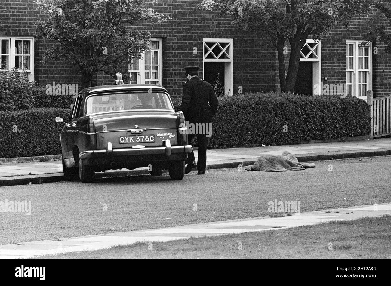Three police officers, Detective Sergeant Christopher Tippett Head, 30, Temporary Detective Constable David Bertram Wombwell, 25 and Police Constable Geoffrey Roger Fox, 41, were shot dead after investigating a battered blue Standard Vanguard estate van parked in Braybrook Street with three men sitting inside it. Harry Roberts, John Edward 'Jack' Witney and John Duddy were convicted of their murder. The scene in Braybrook Street after the murders, a body lies beside the officer's Triumph car. 12th August 1966. Stock Photo