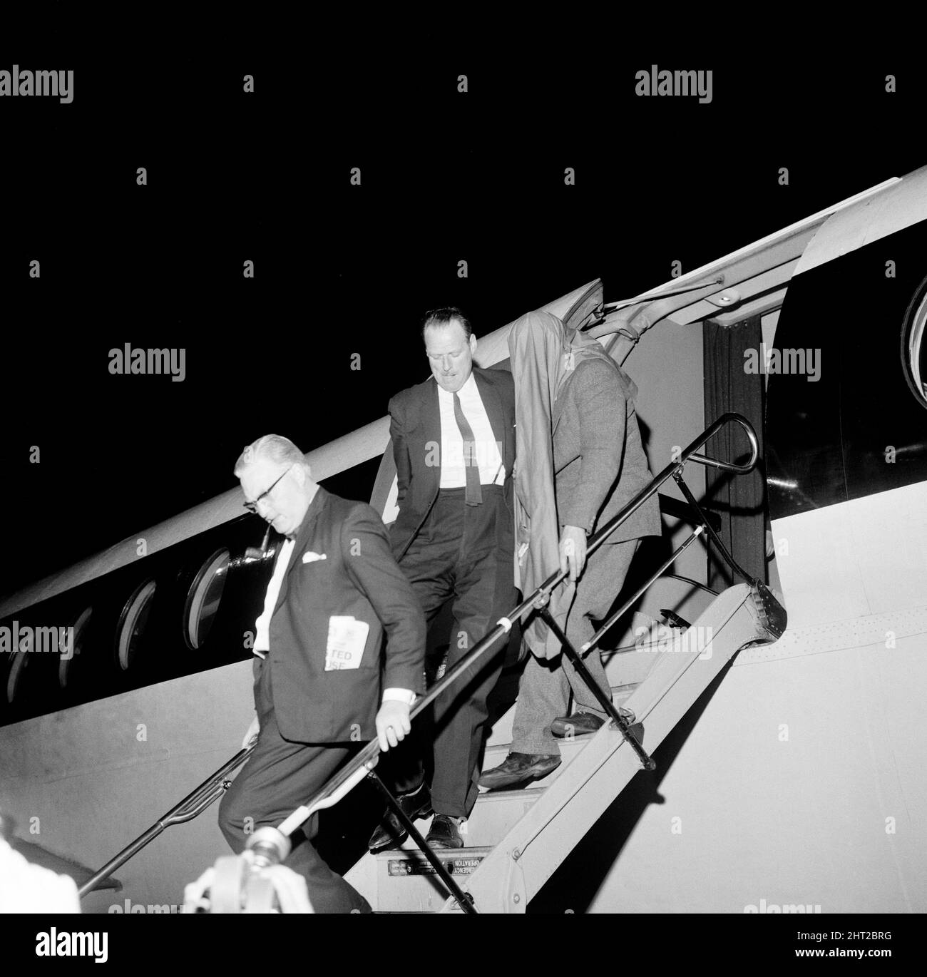John Duddy, 37, one of the men that police wish to interview in connection with the shooting of three policemen in London, is guided down the steps of the plane on arrival at London Airport, from Glasgow, where he was detained this afternoon. 18th August 1966. Stock Photo