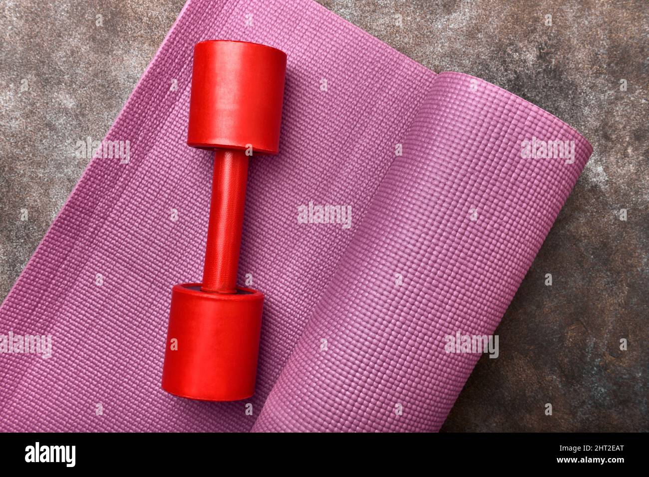 Rubber exercise mat and red dumbbell Stock Photo