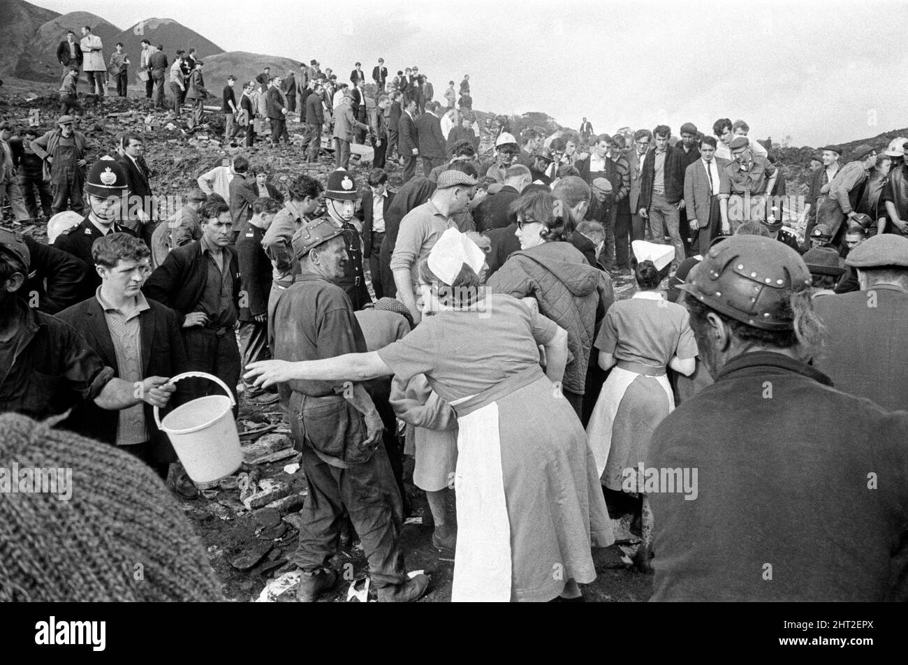 Aberfan, South Wales, circa 21st October 1966 Picture shows the mud and devastation caused when mining spoil from the hillside high above the town behind came down  and engulfed The Pantglas Junior School on 21st October 1966.   Rescuers trying to find victims and help, monist the mud and rubble around the school site.  The Aberfan disaster was a catastrophic collapse of a colliery spoil tip in the Welsh village of Aberfan, near Merthyr Tydfil. It was caused by a build-up of water in the accumulated rock and shale, which suddenly started to slide downhill in the form of slurry and engulfed The Stock Photo