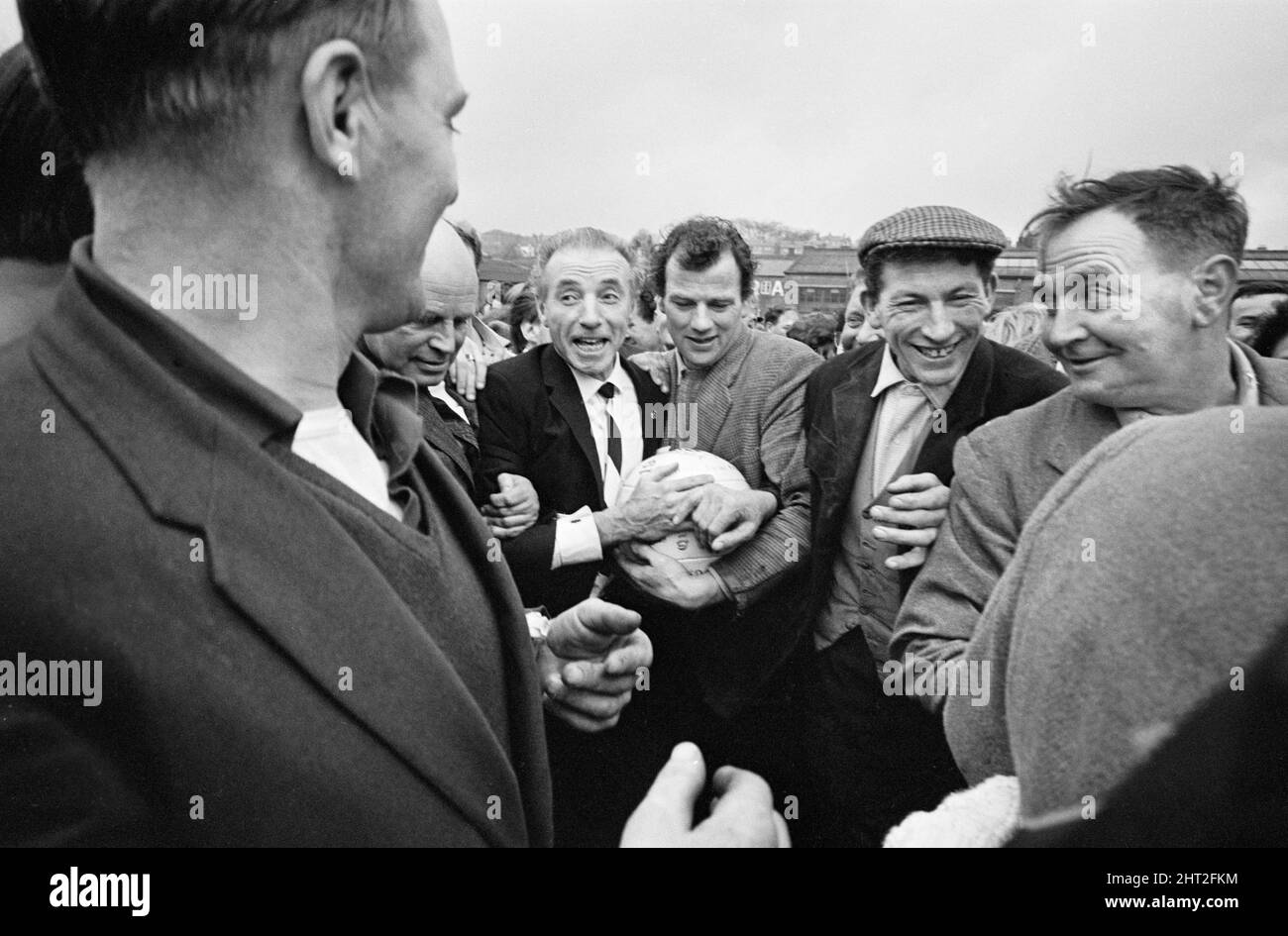 The traditional Royal Shrovetide Football Match, a 'medieval football' game played annually on Shrove Tuesday and Ash Wednesday in the town of Ashbourne in Derbyshire. Guest of honour Sir Stanley Matthews is hustled through the crowd by some hefty villagers toward the start point of the game. 22nd February 1966. Stock Photo