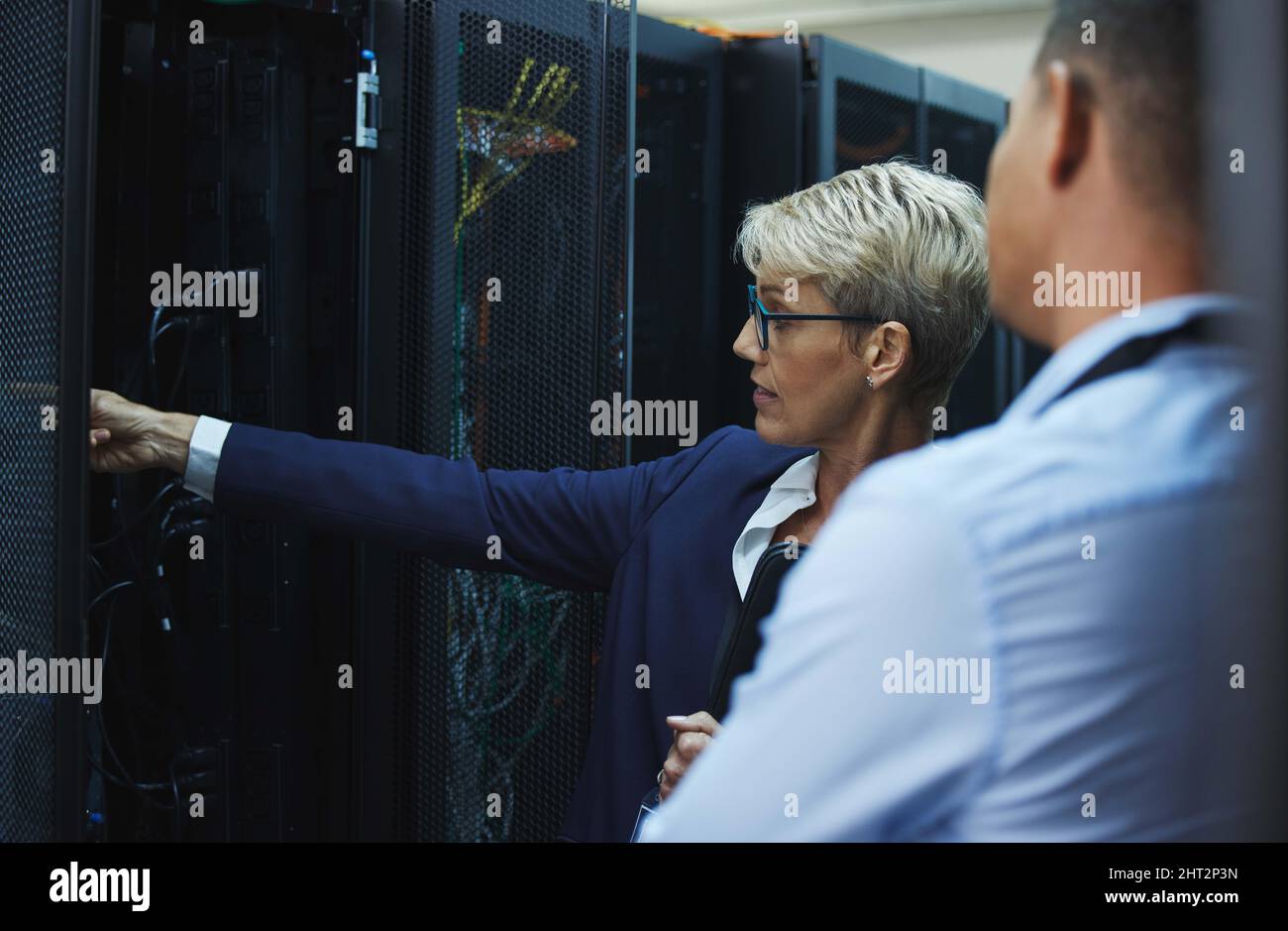 Attention to detail is what makes a leader. Shot of two workers inspecting the electronic equipment in a server room together at work. Stock Photo