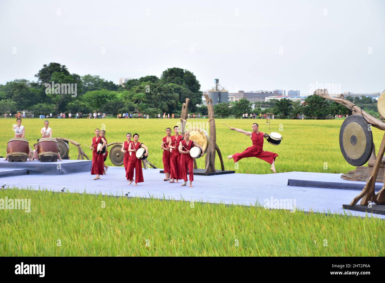 Group of Asian people dancing and playing percussion in a green field in Dongguan, China Stock Photo