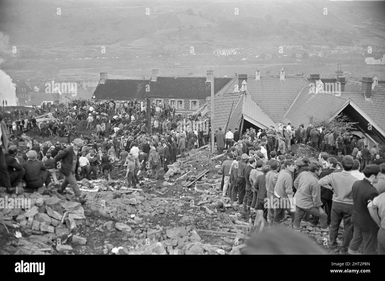 Aberfan - 21st October 1966 Local men and the emergency services hastily dig through the mud for survivors at The Pantglas Junior School.  They form lines so as to move buckets of mud, from one to the other, away from the scene.  And to be in line, moving up the queue for their turn to dig.  The Aberfan disaster was a catastrophic collapse of a colliery spoil tip in the Welsh village of Aberfan, near Merthyr Tydfil. It was caused by a build-up of water in the accumulated rock and shale, which suddenly started to slide downhill in the form of slurry and engulfed The Pantglas Junior School below Stock Photo