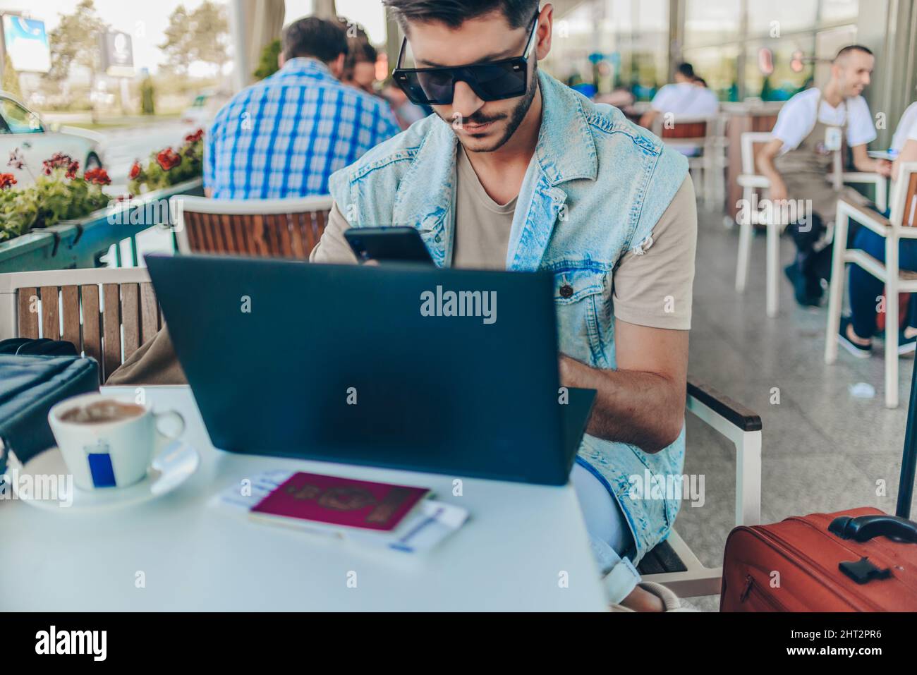 Young man working on laptop while waiting to take off Stock Photo