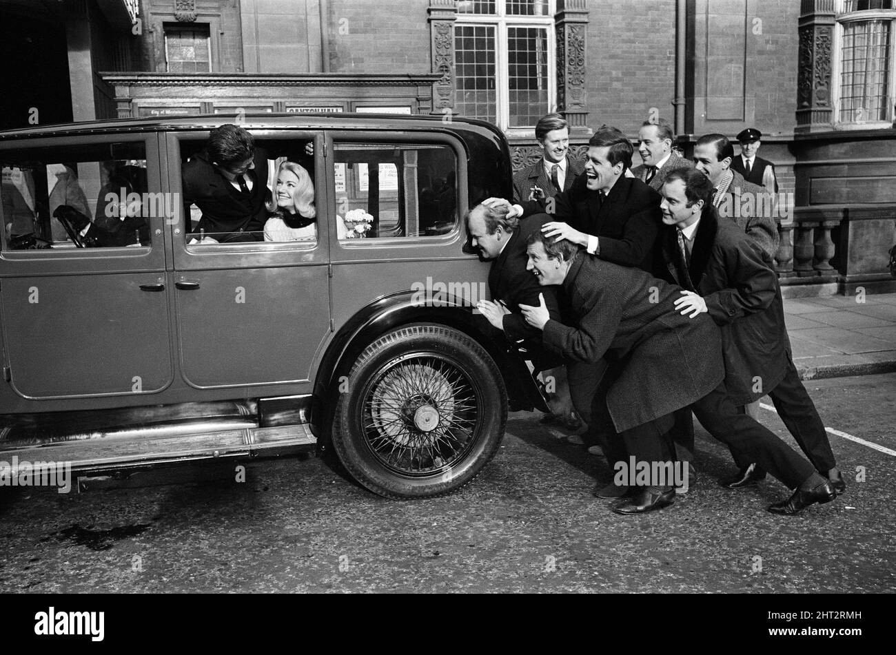 The wedding of Al Mancini and Denny Dayviss at Caxton Hall, London. The eight best men queue to kiss the bride. The bridge and groom are pictured in a 1924 Rolls Royce saloon with the eight best men, Lance Percival, Jack Duncan, Frank Dux, Kenneth Cope, Roy Kinnear, William Rushton, Ronnie Carroll and Ned Sherrin, giving it a push. 23rd November 1965. Stock Photo