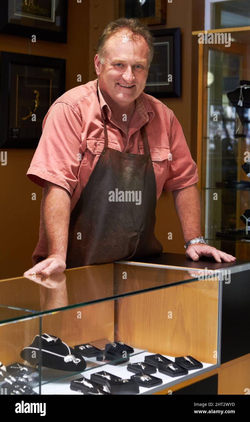Proud of all he displays. Smiling jeweler standing behind the display case in his store. Stock Photo