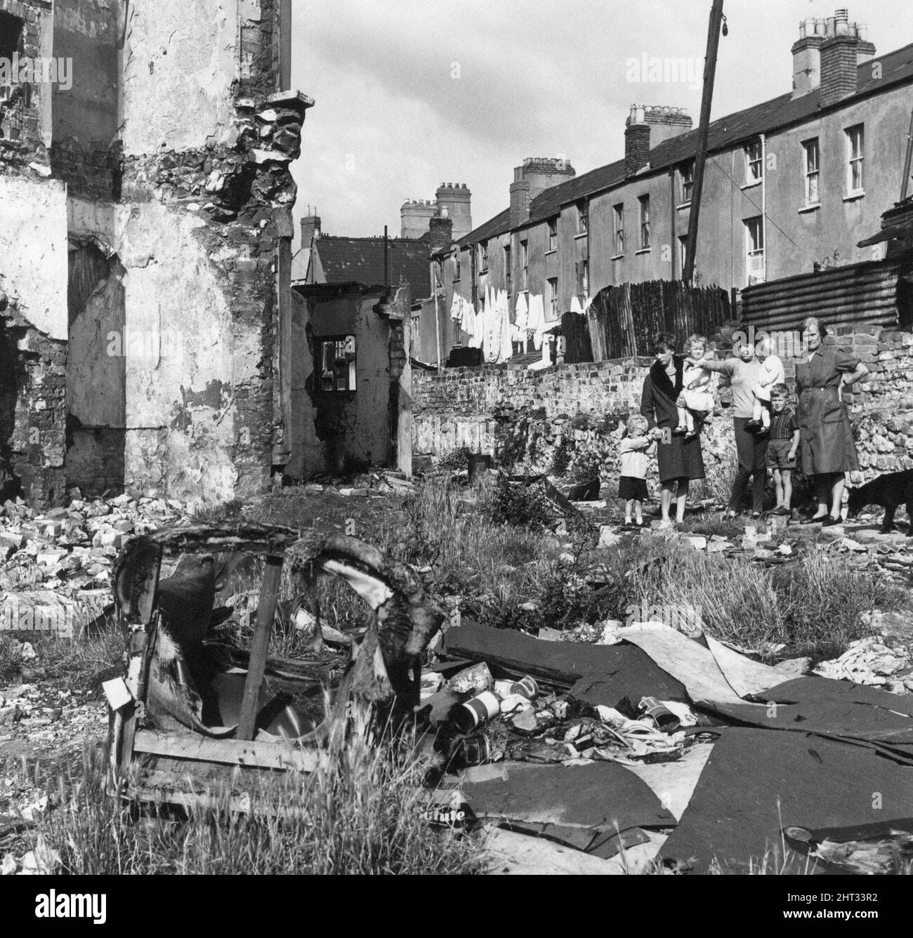 Rubbish site in Adamsdown, an inner city area and community in the south of Cardiff, Wales. 14th January 1965. Our Picture Shows ... three of the residents with their children point out illegal rubbish dump plagued by rats. Left to Right, Mary Adams with her two children John aged 3 and Jullie aged 2, Sally Beaton with Nigel 3 and Allison 15 months and Ellen Olvey. Stock Photo