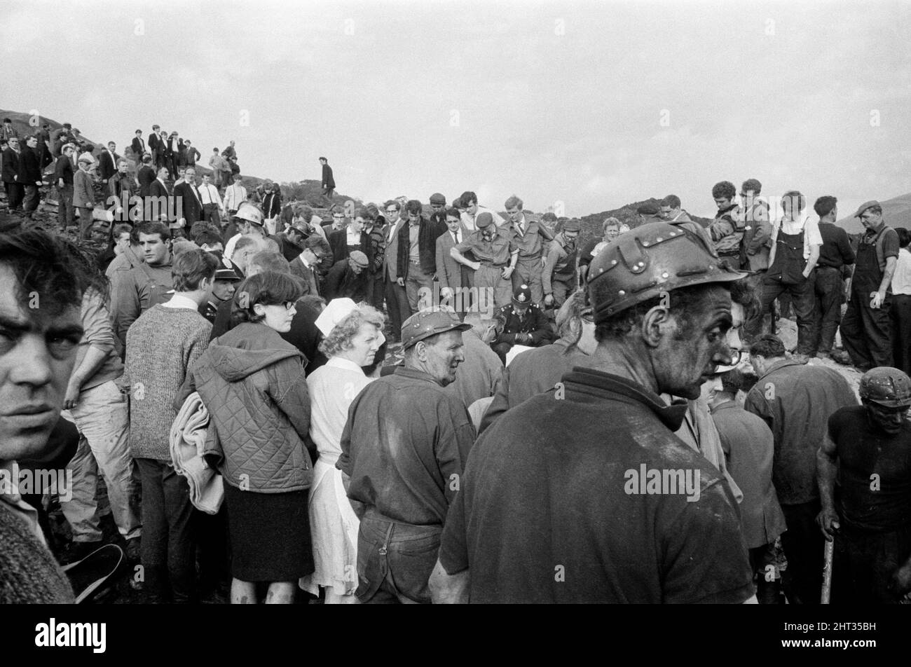 Aberfan, South Wales, circa 21st October 1966 Picture shows the mud and devastation caused when mining spoil from the hillside high above the town behind came down  and engulfed The Pantglas Junior School on 21st October 1966.   Rescuers trying to find victims and help, monist the mud and rubble around the school site.  The Aberfan disaster was a catastrophic collapse of a colliery spoil tip in the Welsh village of Aberfan, near Merthyr Tydfil. It was caused by a build-up of water in the accumulated rock and shale, which suddenly started to slide downhill in the form of slurry and engulfed The Stock Photo