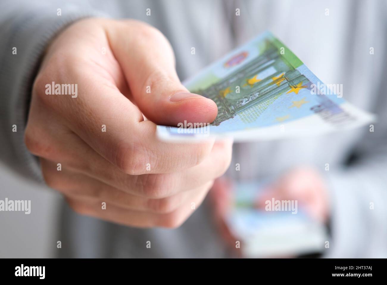 Male hand giving only one money banknote for a payment on white background, close up of caucasian adult man handing out European Union currency, euro. Stock Photo