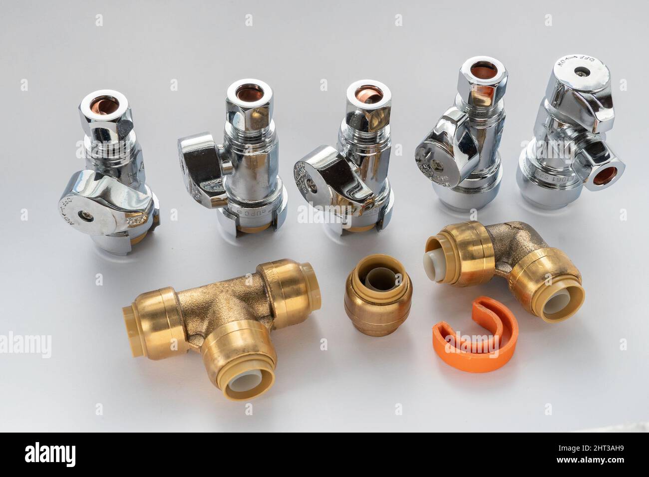 Brass plumbing fittings, pipes, elbows, and end caps, top and side connection faucets against a white background Stock Photo