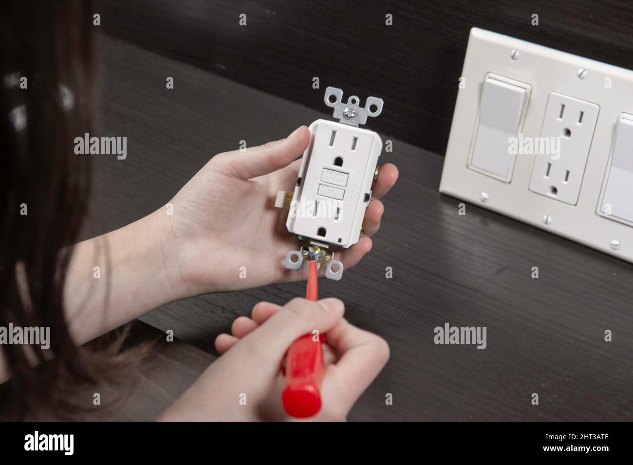 Checking the electrical outlet before installing it in a junction box on the wall Stock Photo
