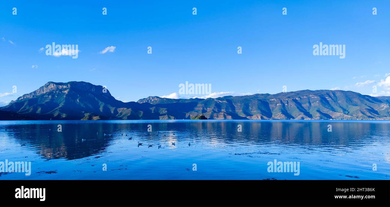 A scenic view of  a calm lake and mountain landscape under clear blue sky Stock Photo