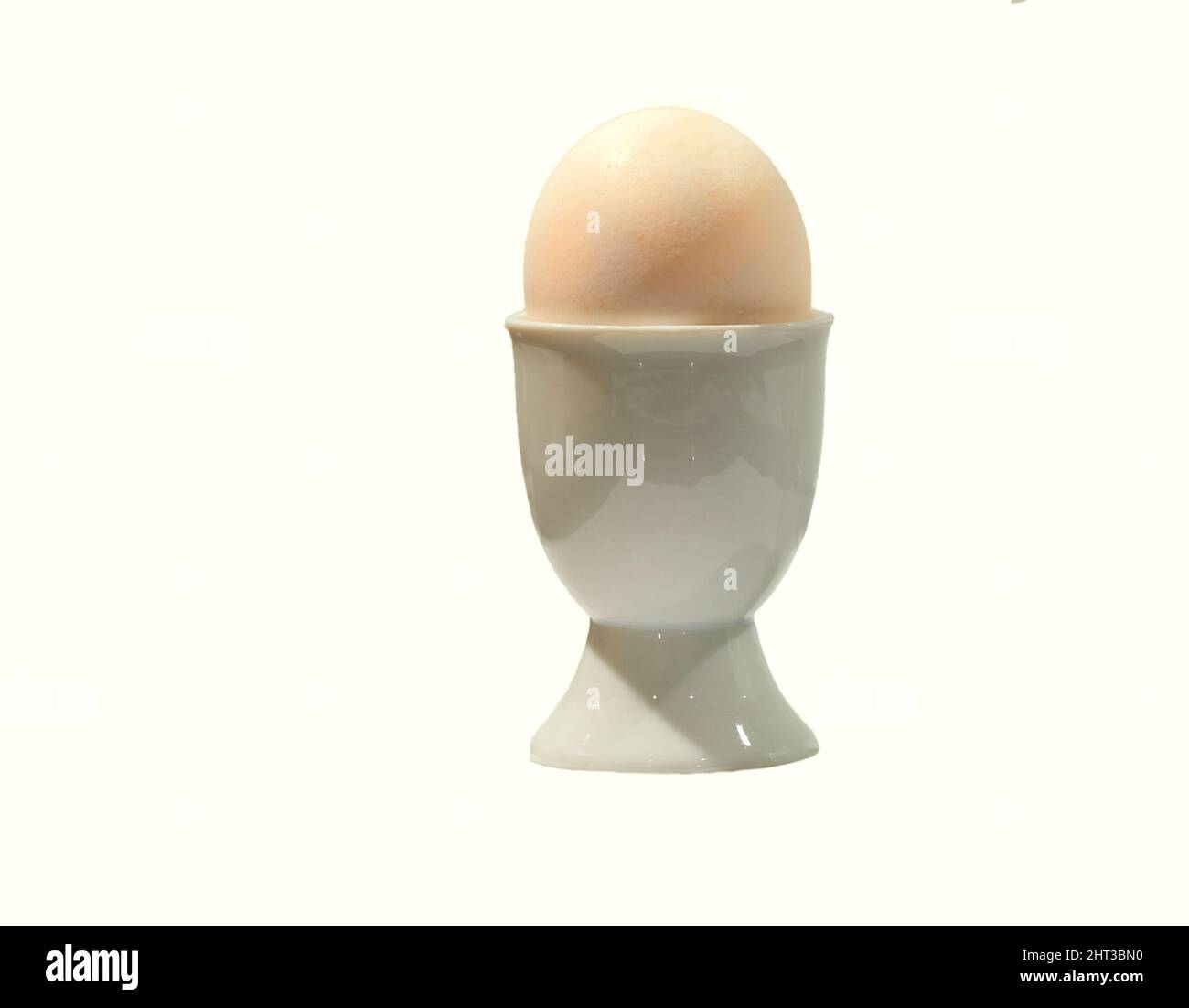 Egg cup. Egg in egg cup on white table top - isolated. Stock Photo