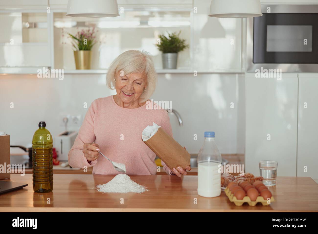 Smiling retired woman enjoying cooking at home Stock Photo